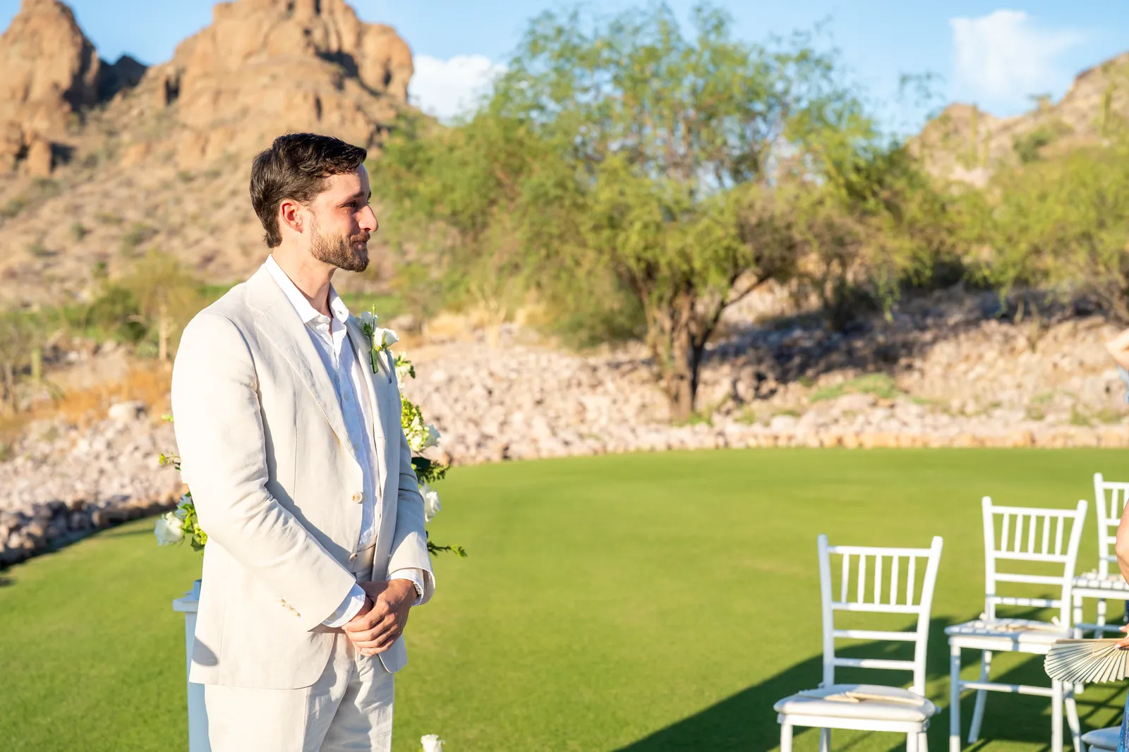 El novio voltea a ver entrar a la novia, junto a las sillas de la ceremonia