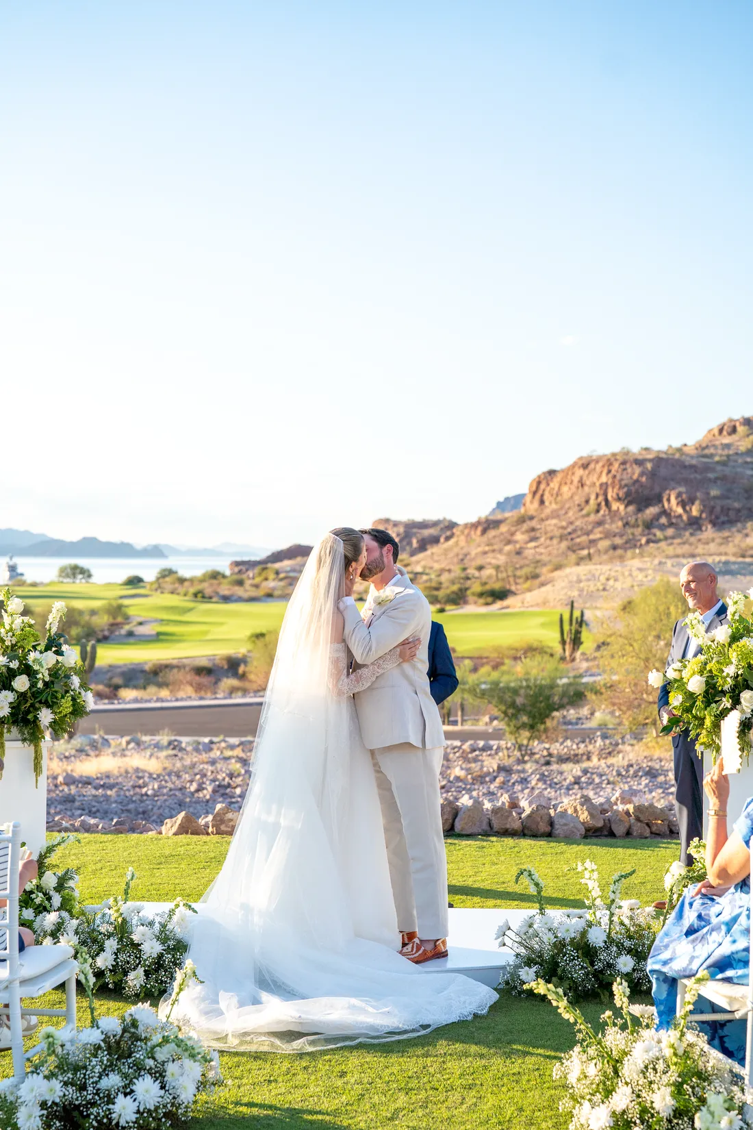El primer beso como esposos junto al arreglo de flores blancas