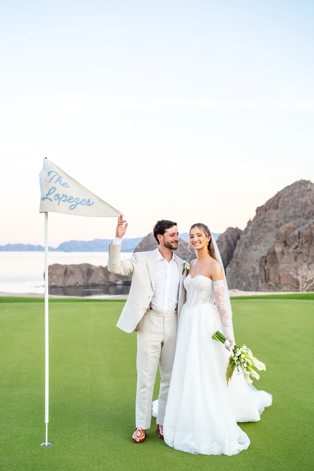 Los novios junto a la bandera del hoyo, personalizada con su apellido