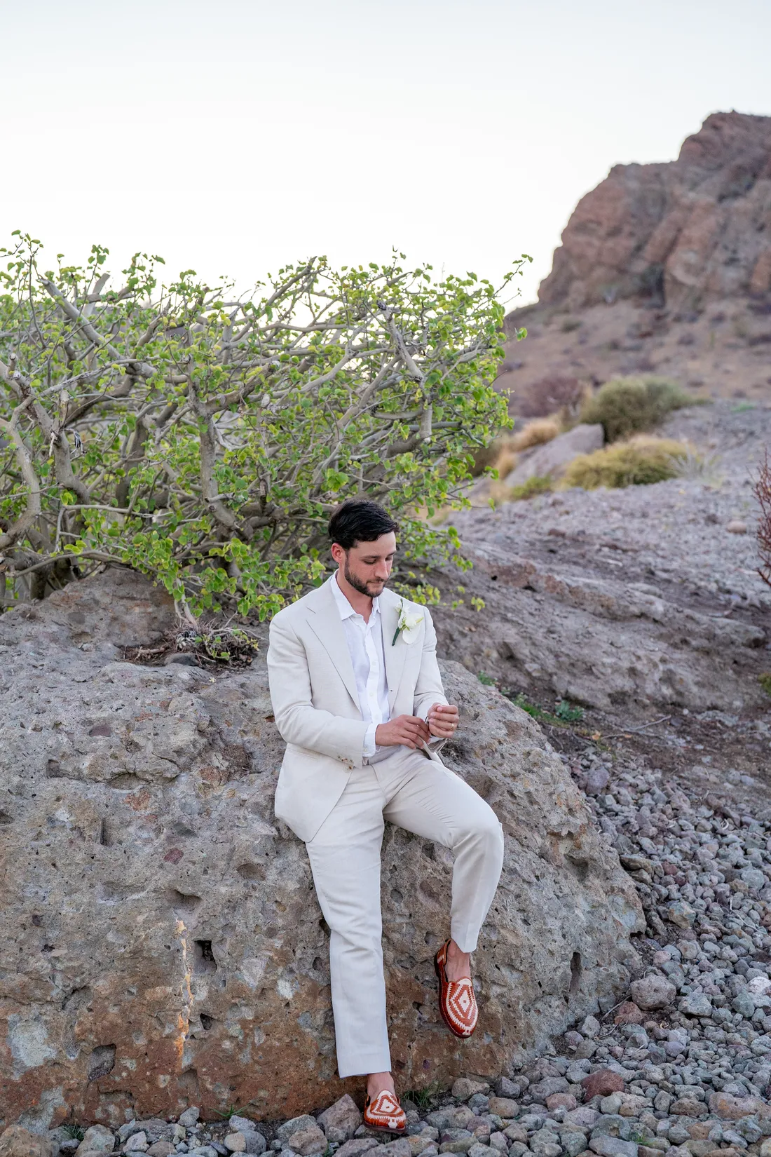 Retrato del novio sentado sobre las rocas del desierto