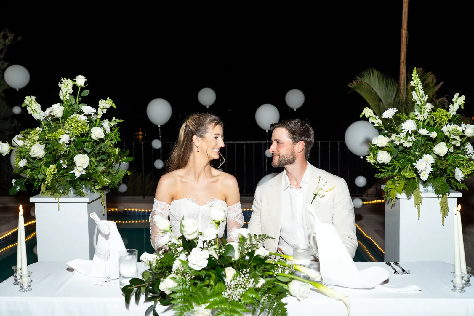Los novios en la mesa principal, rodeados de flores y globos