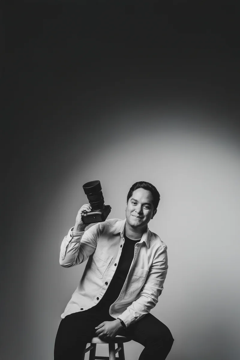César Castro, fotógrafo de bodas en Los Cabos, sentado con su cámara en un retrato de estudio