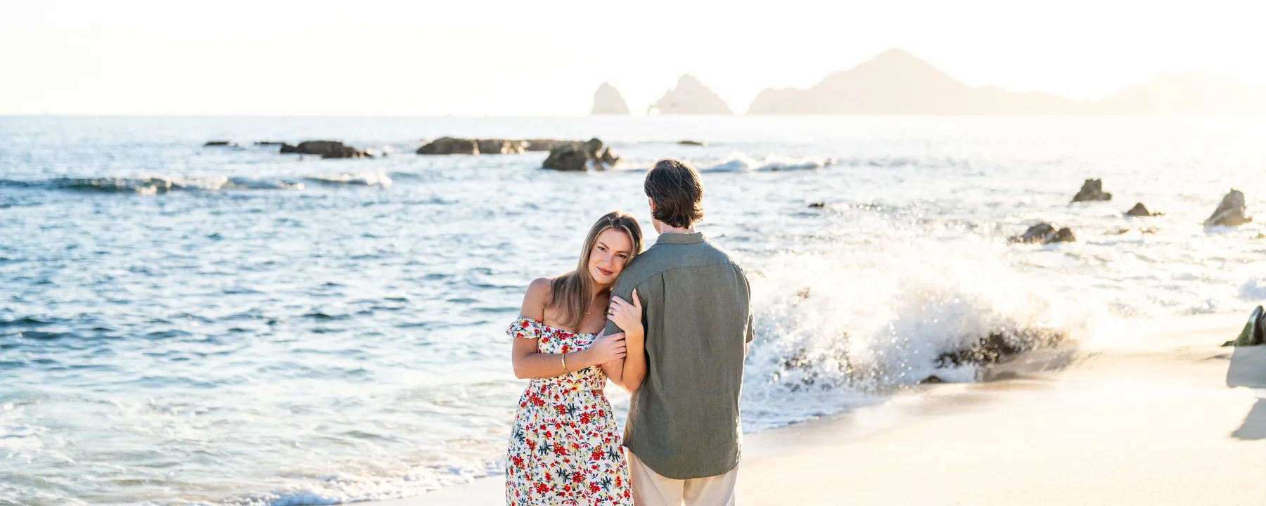 Pareja abrazada en la playa de Cabo San Lucas con El Arco al fondo