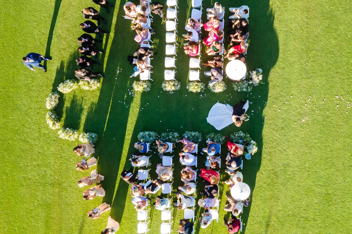 Vista aérea con dron de una ceremonia de boda al aire libre, con los invitados en hileras sobre el pasto