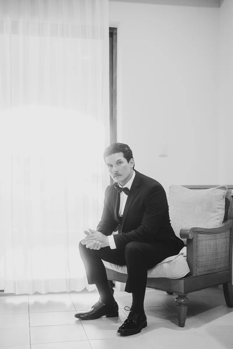 El novio, ya vestido de esmoquin, espera junto a la ventana antes de la ceremonia